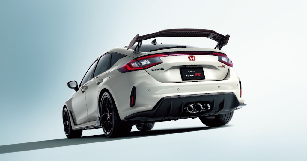 白を基調としたスタジオで、ローアングルから撮影された新型ホンダ・シビックタイプR(FL5型)のリアビュー。特徴的な大型リアウイング、赤いHマークとTYPE Rエンブレム、そしてセンター3本出しマフラーが強調されている。